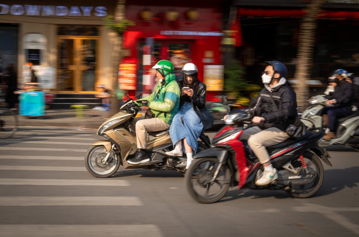 Moto-taxista a transportar um passageiro pelas ruas da cidade